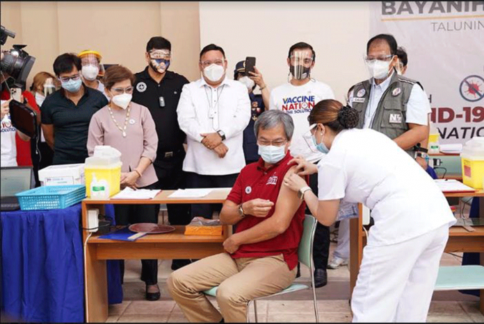 PGH-director-kicks-off-PH’s A health worker injects Sinovac’s coronavirus disease 2019 vaccine at the University of the Philippines-Philippine General Hospital director Dr. Gerardo "Gap" Legaspi in the presence of vaccine czar Carlito Galvez, Jr., Presidential spokesperson Harry Roque, and Manila mayor Isko Moreno. PCOO