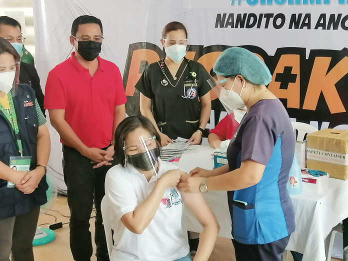 Dr. Edmarie Tormon is the first Capiznon and healthcare worker to receive a vaccine against coronavirus disease 2019 during the vaccine rollout in Capiz province. Gov. Even Esteban Contreras is standing behind Tormon.
