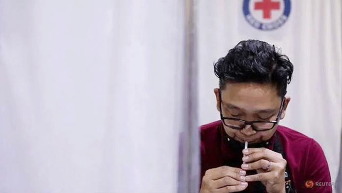 COVID SPIT TEST. This is how the specimen is collected. A man transfers his saliva into a vial for a coronavirus disease 2019 test at a Philippine Red Cross molecular laboratory in Mandaluyong City, Metro Manila. REUTERS