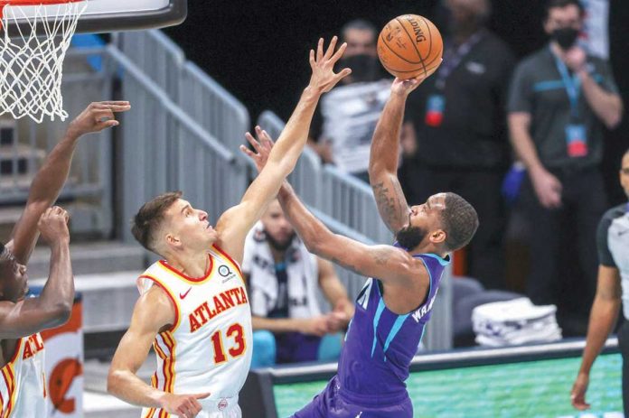 Sports-1-banner Charlotte Hornets’ Brad Wanamaker (right) shoots the ball over Atlanta Hawks’ Bogdan Bogdanovic (left) during the second quarter of their 2020-2021 NBA Season game, April 11, in Charlotte, North Carolina. AP/NELL REDMOND