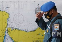 An officer stands in front of a map of the search area for the KRI Nanggala 402. EPA