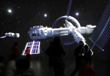 Visitors stand near a giant screen displaying the images of the Tianhe space station at an exhibition featuring the development of China's space exploration on the country's Space Day at China Science and Technology Museum in Beijing. REUTERS/TINGSHU WANG