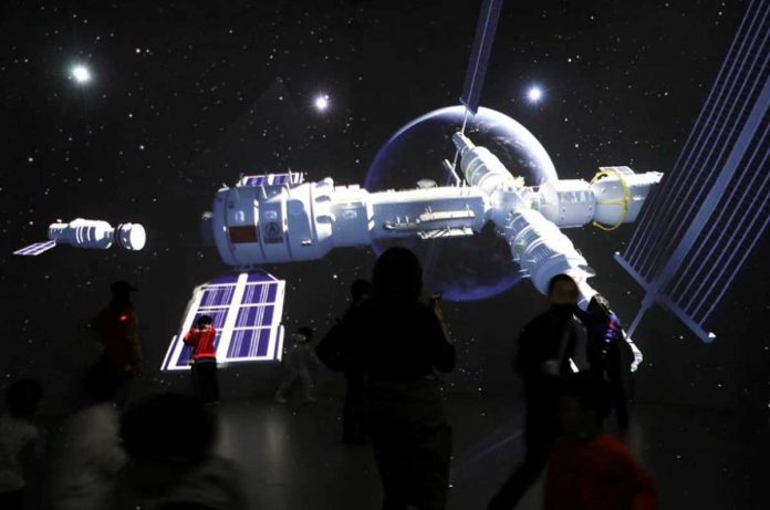 World-2 Visitors stand near a giant screen displaying the images of the Tianhe space station at an exhibition featuring the development of China's space exploration on the country's Space Day at China Science and Technology Museum in Beijing. REUTERS/TINGSHU WANG