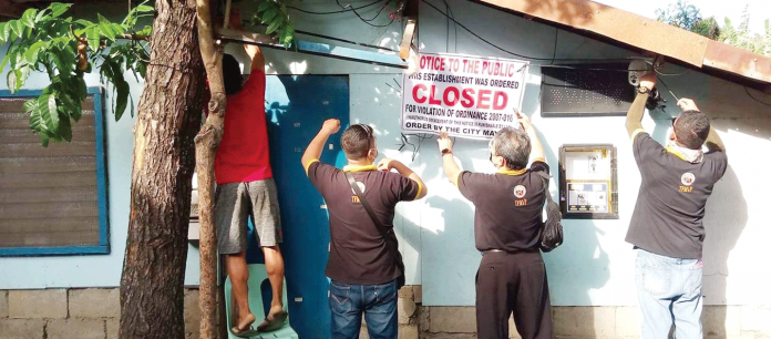 computer-shops-padlocked Personnel of the Iloilo City government’s Task Force on Morals and Values Formation posts a tarpaulin in front of a computer shop closed for allegedly violating the curfew for minors. TFMVF PHOTO