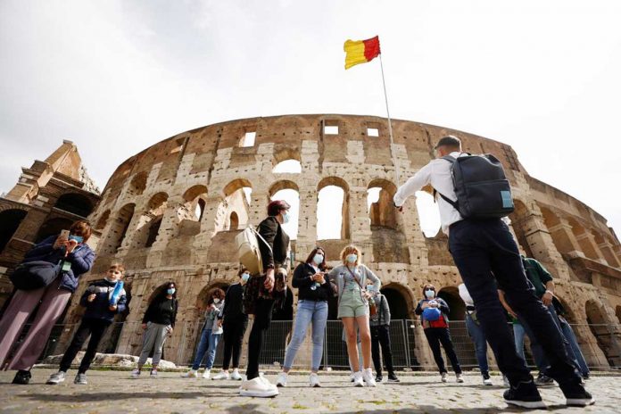 italy-tiptoes People wait outside the Colosseum on the day of its reopening, as much of the country becomes a 'yellow zone', easing coronavirus disease restrictions, in Rome, Italy, April 26. REUTERS/GUGLIELMO MANGIAPANE