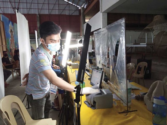 pic-psa A staff of the Philippine Statistics Authority disinfects the equipment used in Step 2 of the registration for the national ID system. PHOTO BY GLENDA TAYONA/PN