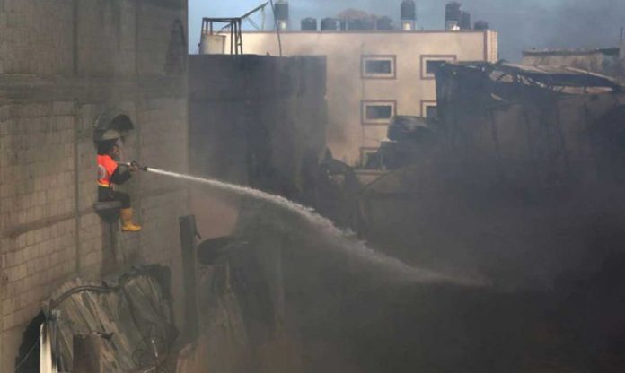 A firefighter puts out a fire at a factory after it was hit by Israeli artillery shells in the northern Gaza Strip on Monday. Israel said the air strikes hit Hamas targets, but homes and other buildings were also damaged. REUTERS/ASHRAF ABU AMRAH