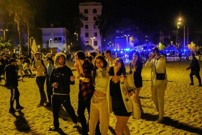 barceloneta-beach People gather in front of police officers patrolling Barceloneta beach, as the state of emergency decreed by the Spanish Government to prevent the spread of COVID-19 was lifted a week ago in Barcelona, Spain, May 15. REUTERS/NACHO DOCE
