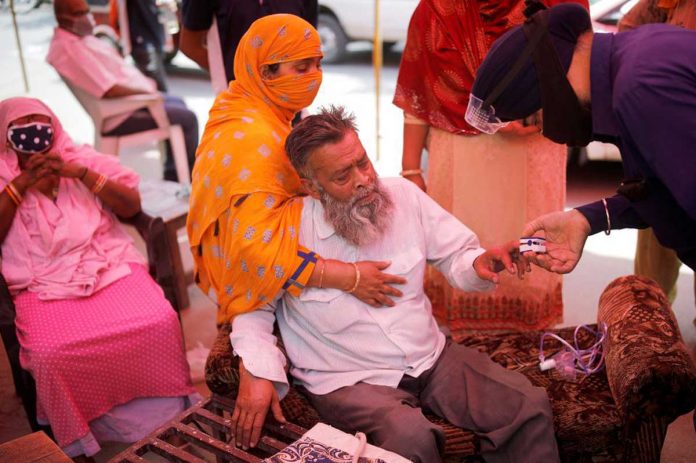 A volunteer uses a pulse oximeter to check the oxygen saturation of a man's blood before providing him oxygen support for free in India during the outbreak of coronavirus disease 2019. REUTERS/ADNAN ABIDI