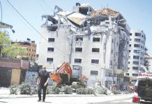 A Palestinian walks by a building hit by an Israeli airstrike in Gaza City. Since the fighting began, the Israeli military has launched hundreds of airstrikes it says are targeting Hamas' militant infrastructure, while Palestinian militants have fired thousands of rockets into Israel. AP PHOTO/HATEM MOUSSA