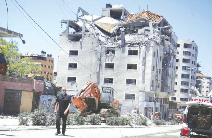 israel-gaza A Palestinian walks by a building hit by an Israeli airstrike in Gaza City. Since the fighting began, the Israeli military has launched hundreds of airstrikes it says are targeting Hamas' militant infrastructure, while Palestinian militants have fired thousands of rockets into Israel. AP PHOTO/HATEM MOUSSA
