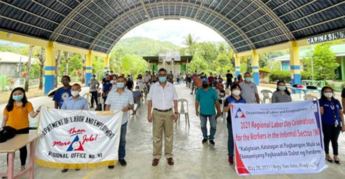 DOLE-6 regional director Cyril Ticao (center) poses with workers from the informal sector at the covered court of Barangay San Jose in Miagao, Iloilo. With him are municipal administrator and PESO manager John Nocal, Miagao’s Mayor Macario Napulan (second and third from left), IFO head Melissa Navarra, and DOLE-6 staff.