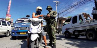 A motorist presents his travel pass to a police officer at a checkpoint in Barangay Mohon, Arevalo, Iloilo City.