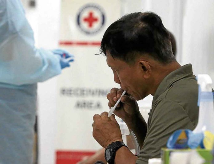 red-cross-saliva-tests A man spits in a small container using straw so his saliva can be collected and tested for COVID-19 at the Philippine Red Cross headquarters in Port Area, Manila. INQUIRER/ MARIANNE BERMUDEZ/FILE PHOTO.