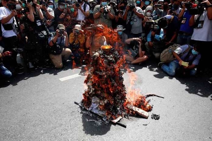 thai-protesters Members of the media take photos of a model of Democracy Monument set on fire by protesters before a march to mark the 89th anniversary of the abolition of absolute monarchy in Bangkok, Thailand, on June 24, 2021. REUTERS/SOE ZEYA TUN