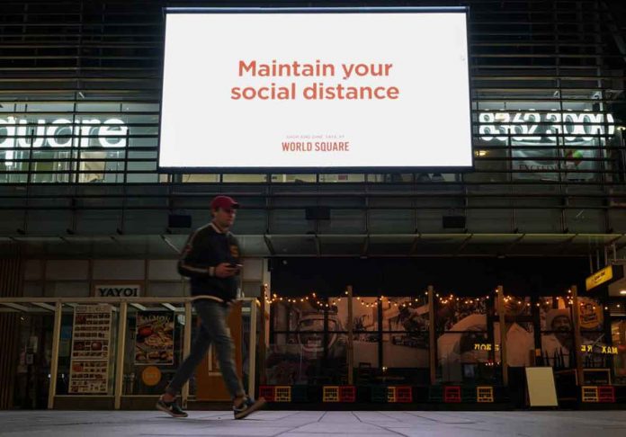 W-1 A man walks under a public health message about social distancing displayed at a shopping plaza in the city center during a lockdown to curb the spread of the COVID-19 outbreak in Sydney, Australia. REUTERS/LOREN ELLIOTT