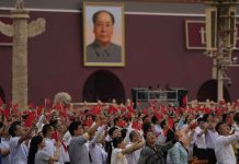 People wave Chinese flags beneath a large portrait of Mao Zedong during a ceremony to mark the 100th anniversary of the founding of the ruling Chinese Communist Party at Tiananmen Gate in Beijing, China. AP PHOTO/NG HAN GUAN