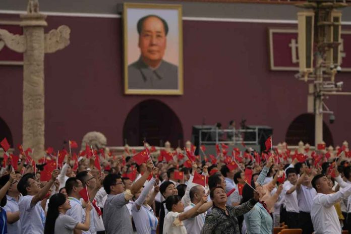People wave Chinese flags beneath a large portrait of Mao Zedong during a ceremony to mark the 100th anniversary of the founding of the ruling Chinese Communist Party at Tiananmen Gate in Beijing, China. AP PHOTO/NG HAN GUAN