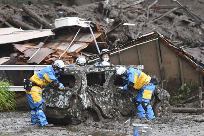mudslide-japan Rescuers check a damaged vehicle at the site of a mudslide in Atami, Shizuoka prefecture. A gush of mud swept away homes and cars in the resort town on Saturday. KYODO NEWS VIA AP