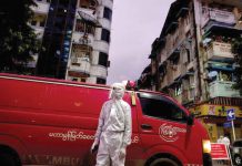 A medical staff wearing a protective suit stands near an ambulance, amid the outbreak of the coronavirus disease, in Yangon, Myanmar. REUTERS/SHWE PAW MYA TIN