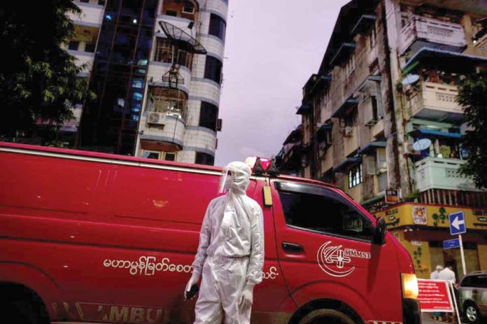 A medical staff wearing a protective suit stands near an ambulance, amid the outbreak of the coronavirus disease, in Yangon, Myanmar. REUTERS/SHWE PAW MYA TIN