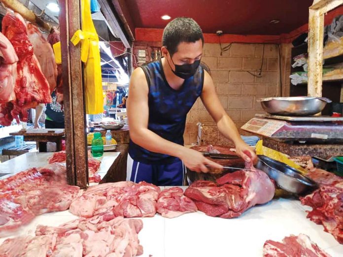 pork Wearing facemask, this meat vendor slices pork for a customer in La Paz Public Market, Iloilo City. On Sunday, Senator Francis Pangilinan urged the government to restore pork tariff rates to their original rates after pork prices remain high. PN FILE PHOTO