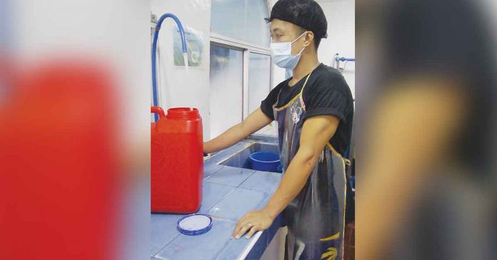 water-refill An employee refills a water container in a refilling station in Mandurriao, Iloilo City. Water refilling stations may have experienced a slight dip in income due to the ill economic effects of the coronavirus disease 2019, but they remain among the essential sectors that continue to survive amid the pandemic. ROANIE DUNGGON
