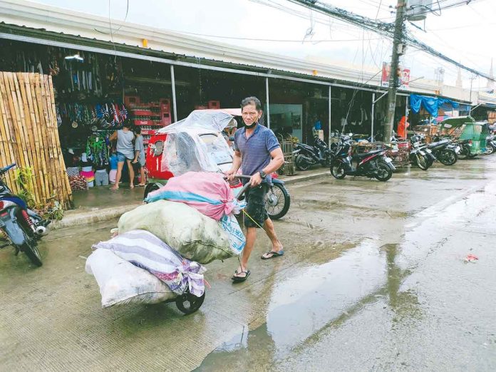 covid-affects-workers Work continues for this porter at the Iloilo Terminal Market despite the bad weather. The coronavirus disease health crisis has forced nearly 100,000 Western Visayans to leave their workplaces and look for other sources of income. PANAY NEWS PHOTO