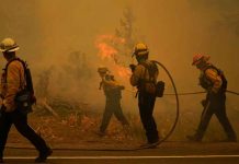 Thousands flee as fire closes in on Lake Tahoe Firefighters carry water hoses while battling the Caldor Fire near South Lake Tahoe, California, on Tuesday. JAE HONG/AP