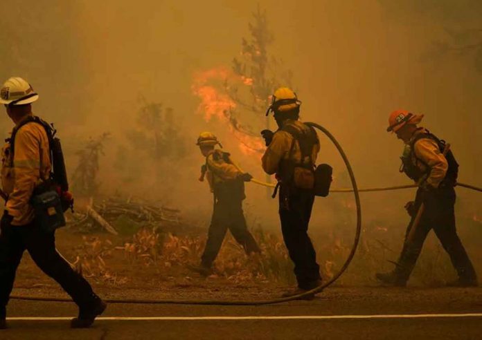 Firefighters carry water hoses while battling the Caldor Fire near South Lake Tahoe, California, on Tuesday. JAE HONG/AP