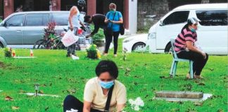 A woman arranges flowers for a departed loved one at a memorial park in Mandurriao, Iloilo City. The Archdiocese of Jaro encourages devotees to offer prayers through Mass – physical or online – and adhere to the minimum health standards while in cemeteries. PANAY NEWS PHOTO