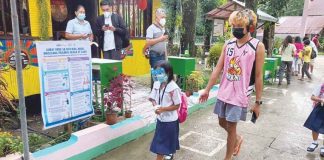 A learner walks with a guardian on the first day of the limited face-to-face classes in Laserna Integrated School in Nabas, Aklan. HERNANI ESCULLAR JR/DEPED-6 PHOTO