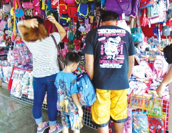 front-pic SIDEWALK SHOPPING. A young boy patiently waits for his Christmas present as his father and mother check this sidewalk stall for toys and other items in downtown Iloilo City. Early this December, the government kicked off the annual holiday campaign “Ligtas Christmas sa Healthy Pilipinas” to guide the public on easy and doable ways to safely celebrate the holiday season. PN PHOTO