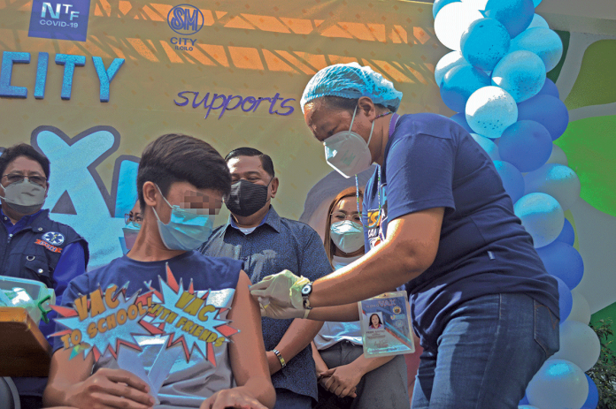 A youngster avails himself of an anti-coronavirus vaccine on the first day of the “Bayanihan Bakunahan” national vaccination drive at SM City Iloilo. PANAY NEWS PHOTO