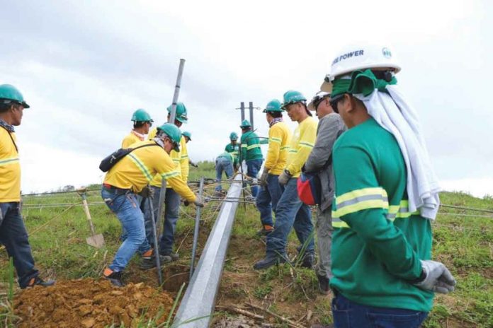 Engineers and line warriors of MORE Electric and Power Corp help one another to re-erect this electric pole that super typhoon “Odette” toppled in southern Negros Occidental.
