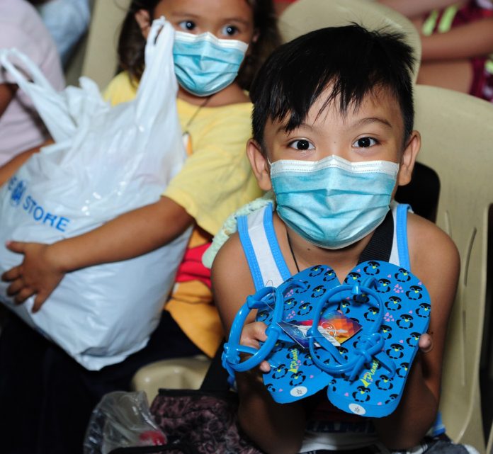 This young boy from San Bartolome De Novaliches Parish is happy to receive this new pair of slippers from the Share Your Extras project turn-over.
