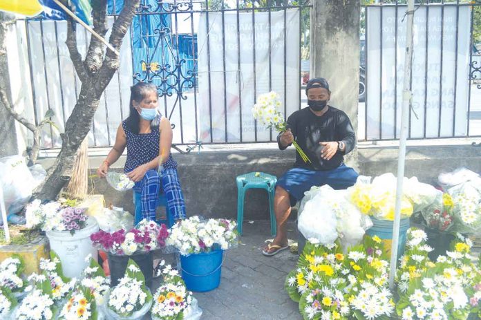 jaro-fiesta-vendors Vendors selling flowers, candles and religious articles wait for buyers outside the Jaro Metropolitan Cathedral in Iloilo City. Restrictions on the movement of people due to the coronavirus pandemic have reduced their volume of customers. PN PHOTOS