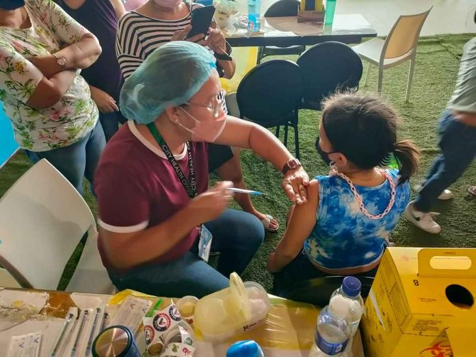 news-ime-kids-(2) BRAVE GIRL. A young girl stays still while being vaccinated against coronavirus disease 2019 at SMs City Iloilo in Mandurriao district. PH PHOTO
