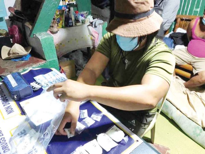 front-dom-bust A police operative is conducting an inventory of the items – sachets of suspected shabu – seized in a buy-bust operation in Purok Katilingban, Barangay Banago, Bacolod City.