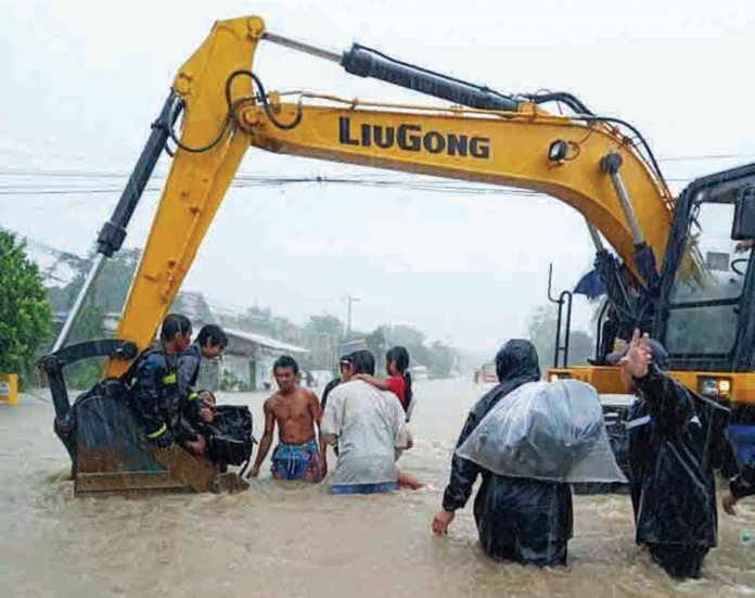 SAVING LIVES. Rescuers use a backhoe to lift people stuck in murky floodwaters in Barangay Anoring, Sara, Iloilo. Of Sara’s 42 barangays, 34 are flooded. Over 6,000 residents have moved to safer grounds. PHOTO FROM SARA GUGMA KO FACEBOOK PAGE