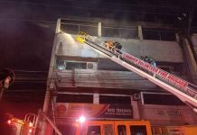 Firefighters use a long ladder to get to the upper floors of this fire-hit building in Bacolod City on Monday night, April 25. Smoke can be seen billowing from the building. BFP-BACOLOD PHOTO