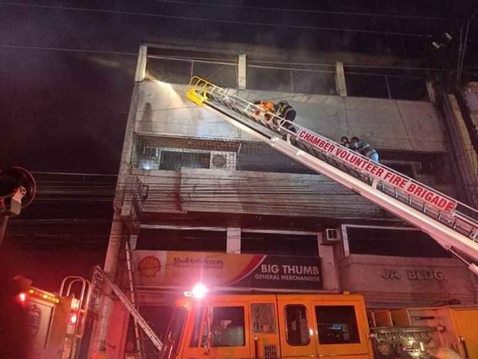 news-dom-rescue Firefighters use a long ladder to get to the upper floors of this fire-hit building in Bacolod City on Monday night, April 25. Smoke can be seen billowing from the building. BFP-BACOLOD PHOTO