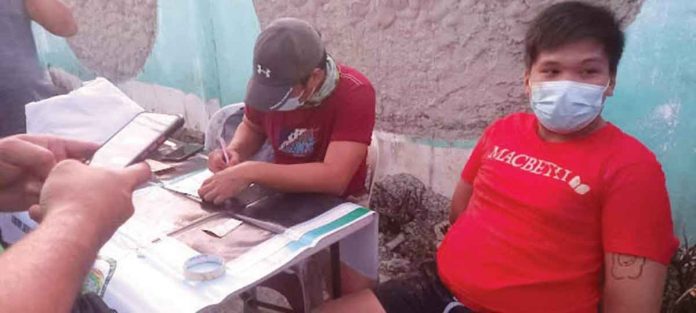 region1 A police operative (right) is going over the items seized in a buy-bust operation in Numancia, Aklan. Seated next to him is the arrested drug suspect, Renz Lloyd Milloroso Rasgo. PHOTO BY RODNEL AGUIRRE, RMN DYKR KALIBO