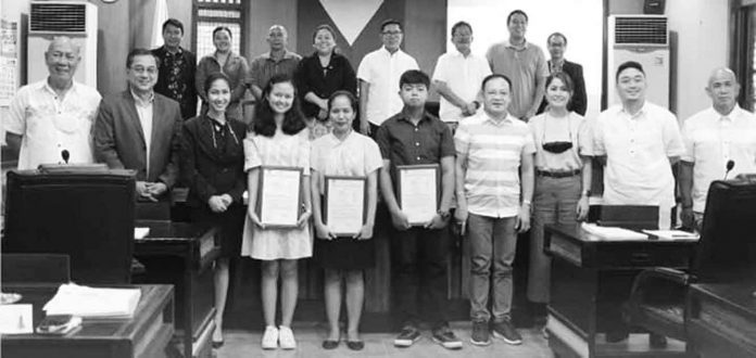Board exam topnotchers Rodriner Billones, Queenstant Dianne Jean Banico and Lenery Ponsaran hold copies of the Capiz Sangguniang Panlalawigan’s resolution commending their feat. They are shown here with members of the Provincial Board. PHOTO FROM THE CAPIZ PROVINCIAL GOVERNMENT COMMUNICATION GROUP FACEBOOK