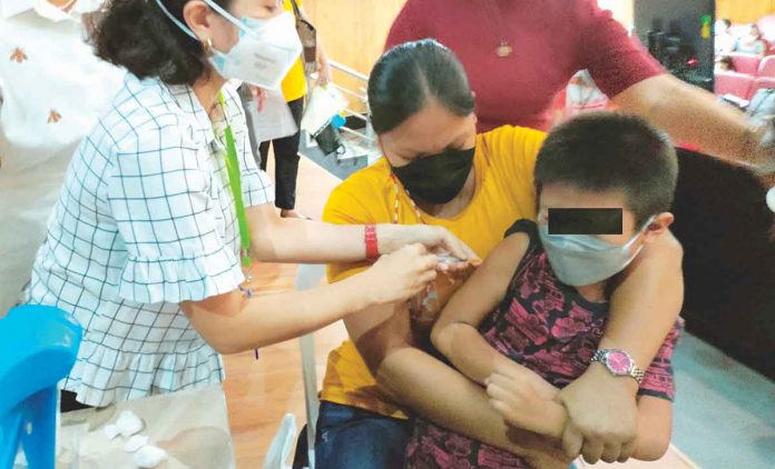 front-integrate A boy gets a shot of the vaccine against coronavirus disease while being restrained by his mother, in this photo taken during the kickoff of the Iloilo provincial government’s vaccination campaign for young children early this year. PN PHOTO
