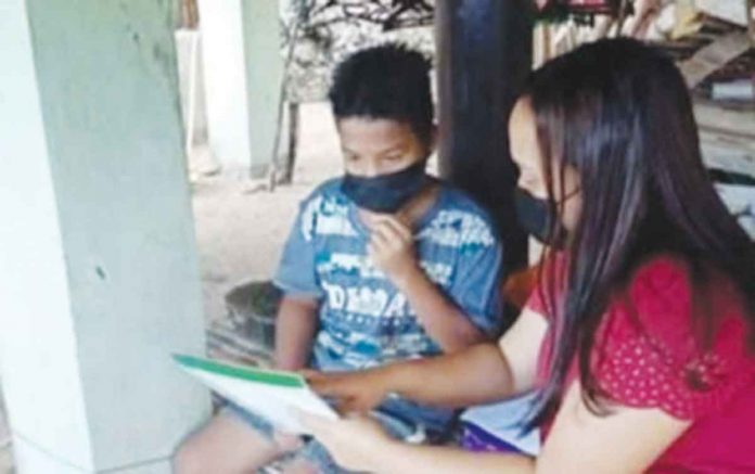 antique A para-teacher, hired under the Department of Labor and Employment (DOLE) Government Internship Program, assists a learner of the Department of Education in this June 2021 photo.