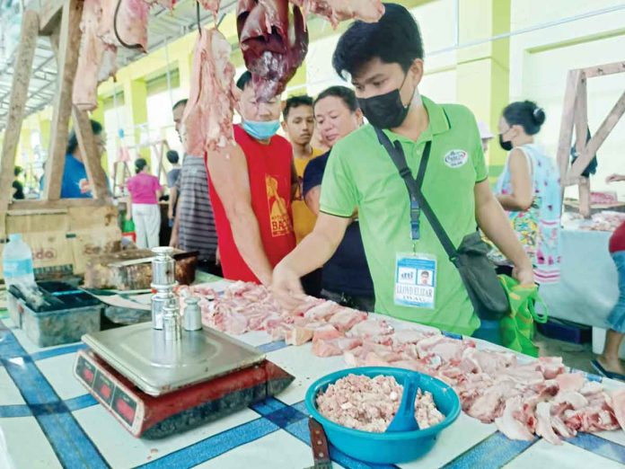 biz2 A personnel of the Department of Trade and Industry checks a weigh scale at the public market of Patnongon, Antique. PIA PHOTO