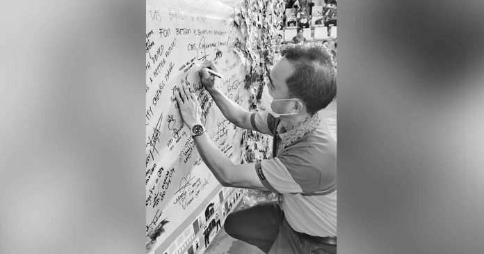 capiz-hosts-brigada-eskwela Capiz Schools Division Superintendent Dr. Miguel Mac Aposin signs a the “commitment board” during the Brigada Eskwela regional kick off in Roxas City. Aposin commits to promote the bayanihan spirit for a safer, healthier and better learning environment for learners. PHOTO BY MERLINDA BAGNATE