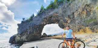 In this Philippine News Agency undated photo, a biker poses for a souvenir photo with the famous Boracay Keyhole behind him. The unique rock formation sits along NewCoast, a new mixed-use leisure and resort development on the world-famous island.