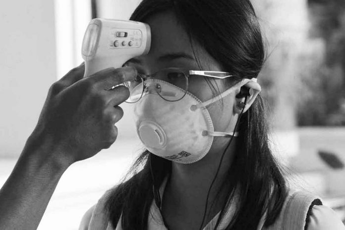 A student wearing a protective facemask gets her temperature taken while entering her college campus in Manila. PHOTO BY TED ALJIBE/AFP